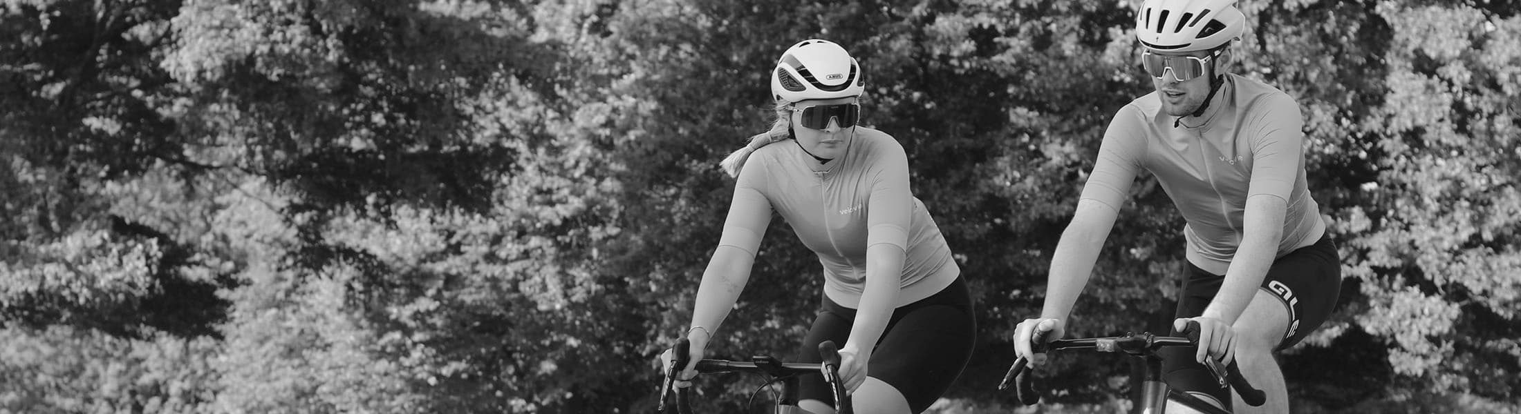 Elle & Cameron testing Element Jerseys in Richmond Park, black and white photo cycling against trees