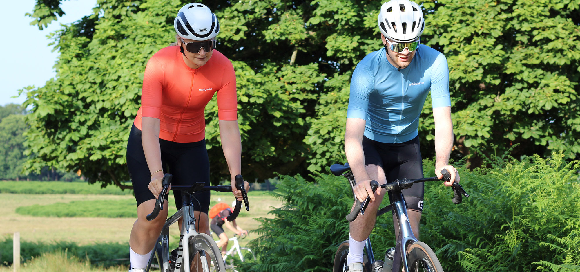 Two cyclists riding bicycles on a path with greenery in the background